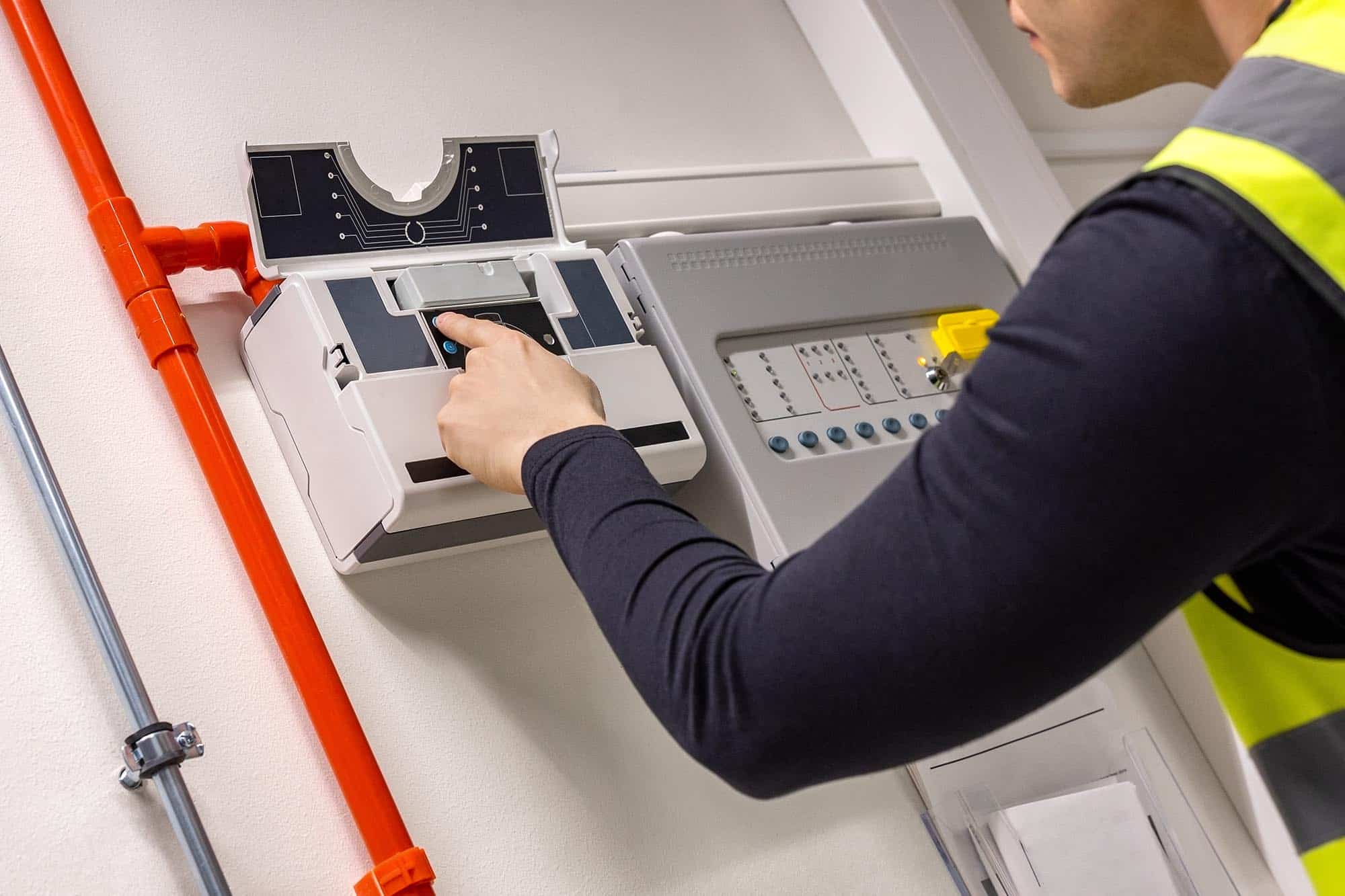 Male Technician Checking Smoke Detector In Datacenter Technical-Specialists
